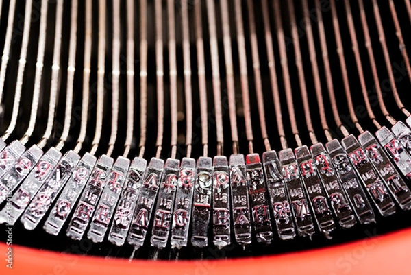 Fototapeta A close-up or a macro shot of the typebars of a retro-style manual typewriter encased in a hinged red top cover.