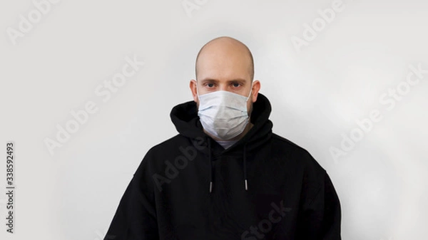 Fototapeta  A man with a beard coughs and puts on a medical mask isolated