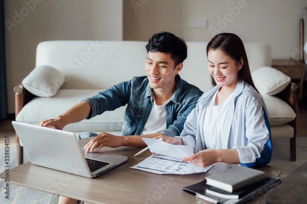 Fototapeta Young Asian couple at home using computer