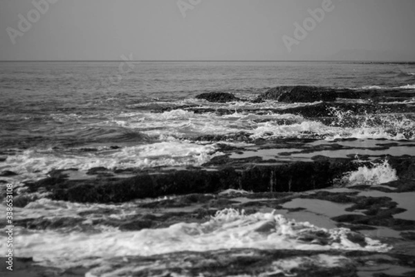 Obraz A black and white shot of the Indian Ocean waves crashing on Rocky beach of Neil Island