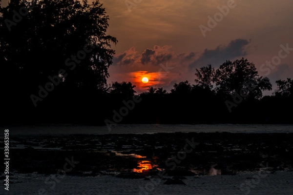 Fototapeta A shot of Beach silhouette with interesting cloudscape and sun and its reflection