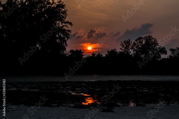 Fototapeta A shot of Beach silhouette with interesting cloudscape and sun and its reflection