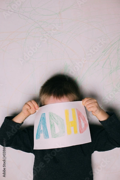 Fototapeta Young boy hold ADHD text written on sheet of paper