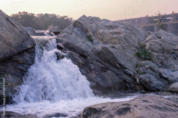 Fototapeta a small waterfall failing down between the rocks downhill