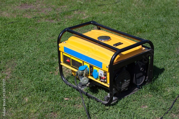 Fototapeta Powerful portable gas or diesel generator to provide electricity. Standing on the grass