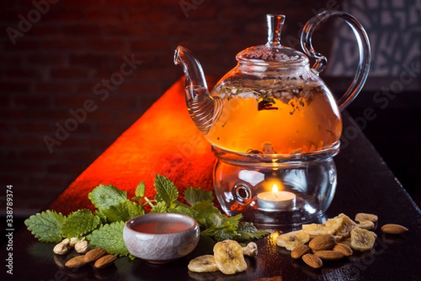 Fototapeta Natural tea.
Pour boiling water in a glass teapot, the ingredients are nearby