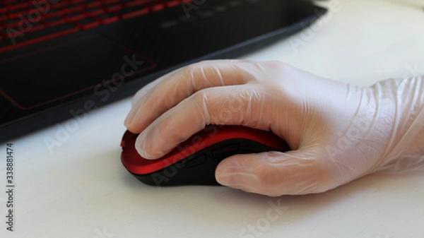 Fototapeta Woman is holding red stylish mouse by her hand, close up. Doctor or nurse or office worker using protective gloves while using computer mouse working at PC at hospital or work in order to stop