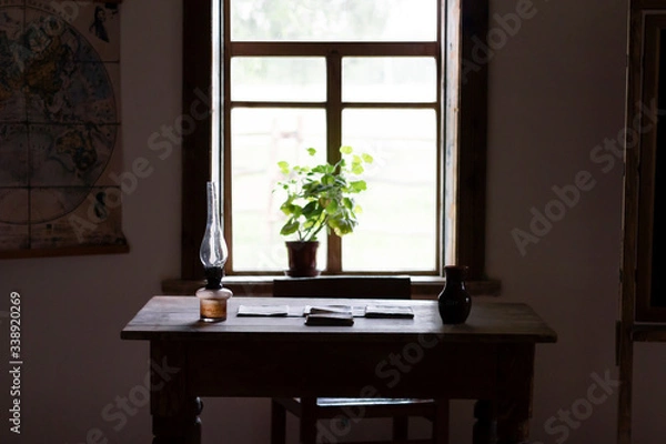 Obraz Old table with papers and a kerasin lamp by the window in a room with natural dim light. Vintage interior in an old house.