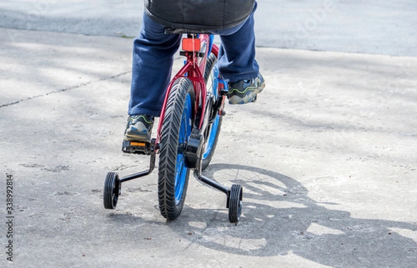 Obraz  Child learning to ride a bike with training wheels