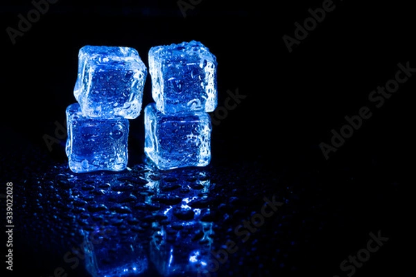 Fototapeta Blue ice cubes reflection on black table background.