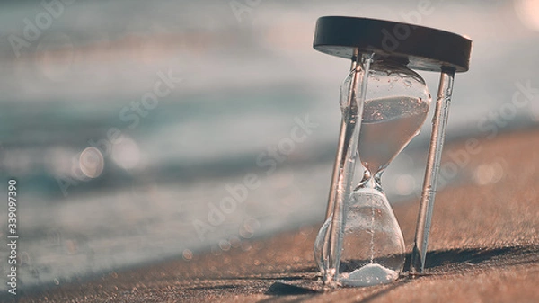 Obraz Hourglass at beach coast as time passing concept for business deadline, urgency and running out of time.