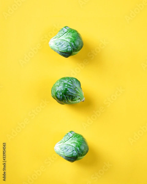 Obraz Small cabbage on a yellow background composed of several slices, cabbage on a colored background, vegetable on a colored background
