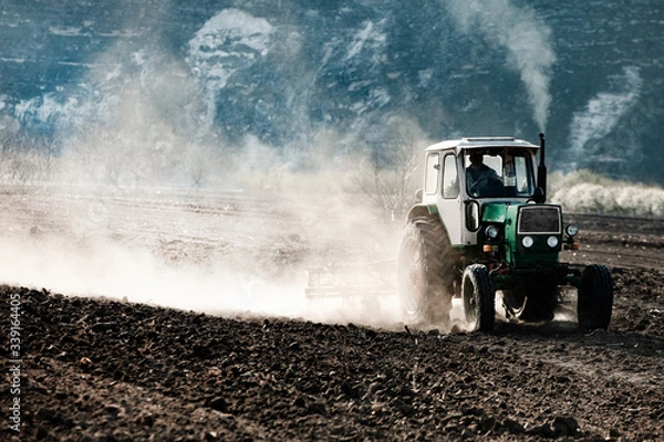 Fototapeta Farmer in tractor preparing land. Agricultural works at farmlands. agricultural work plowing land on a  tractor. Tractor on a farmer field in Moldova, Europe.