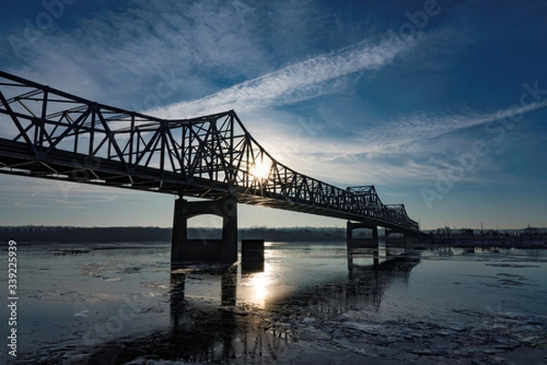 Fototapeta Bridge over Icy river at dawn with cloudscape