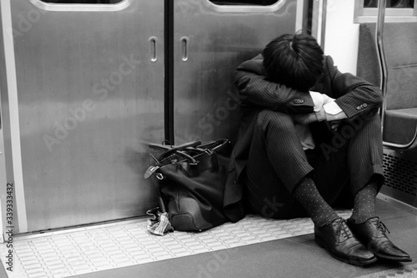 Obraz 電車のドアの前でうずくまるサラリーマン