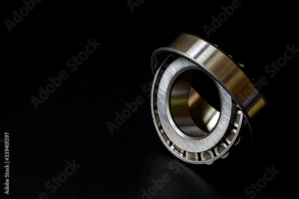 Fototapeta Tapered roller bearing with copy space for your text. Spare part of mechanical on black background..