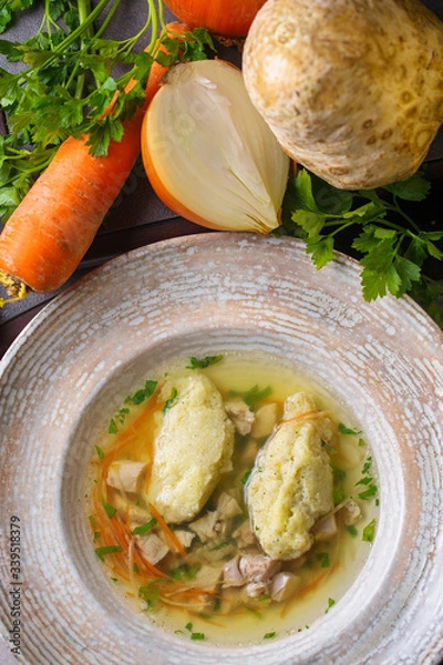 Fototapeta Soup with dill,celery root,carrots,cabbage and potatoes.Soup in a white bowl.Next to the bowl is cut potatoes,carrots and  dill.