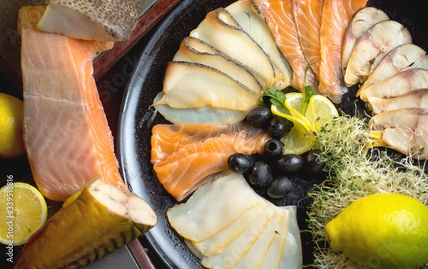 Fototapeta Fish set of varieties of fish,olives,red fish,salmon and seafood.The set is decorated with lemons and all products are laid out on a plate.
