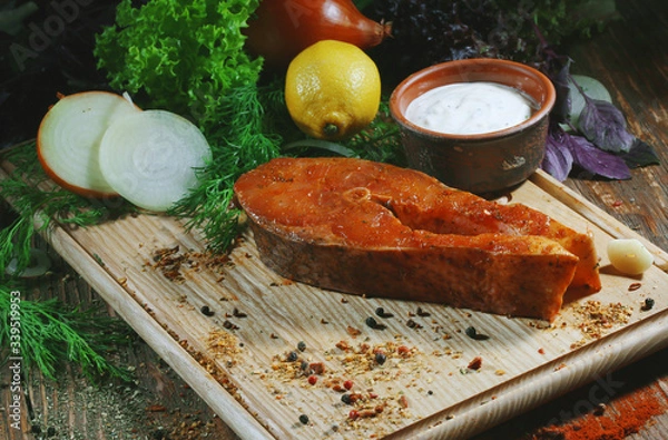 Fototapeta Pickled raw red fish lies on a light board with dill, lemon and seasonings.