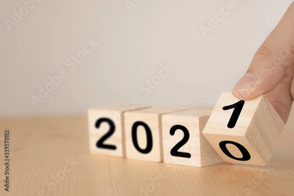 Fototapeta Hand flipping wooden blocks for change year  2020 to 2021 . New year and holiday concept.