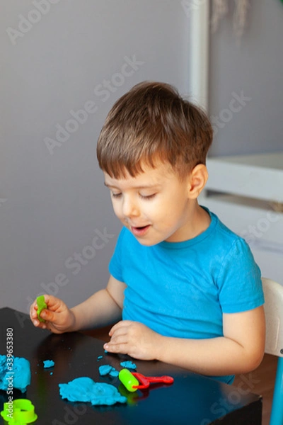 Fototapeta Boy playing with colorful clay molding in your room a Small child sculpts at home. Educational games for preschool children