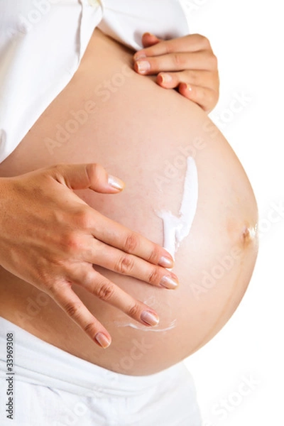 Obraz Pregnant woman moisturising belly to avoid stretch marks