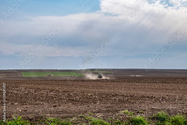 Fototapeta Tractor ploughing(plowing) field in early spring