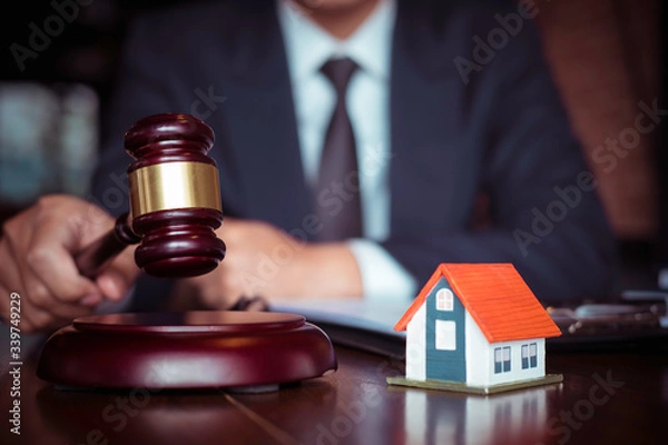 Fototapeta Real Estate Law concept. Gavel on sounding block in hand's Male judge at a courtroom, working for the insurance compensations. report the case on table in modern office.