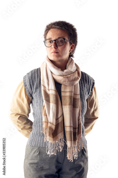 Fototapeta A woman with glasses and a short haircut, in a gray knitted vest, in a shirt and with a scarf around her neck poses on a white background in the studio.