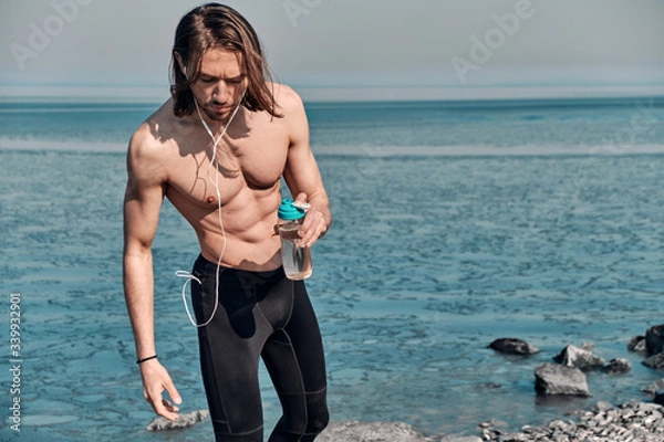 Obraz Shot of Topless Healthy Handsome Active Man With Fit Muscular Body standing outdoors holding water bottle. Fitness man taking a break after running workout.