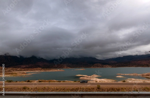 Obraz Lake by a road over a cloudy sky