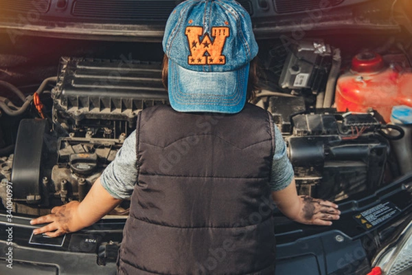 Fototapeta Little child trying to fix broken real car. Dreaming to be auto technician. View from the back