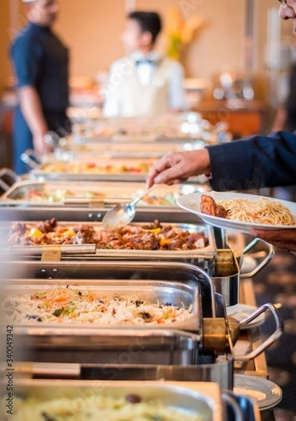 Fototapeta A person serving his meal to a white plate from a buffet in a hotel