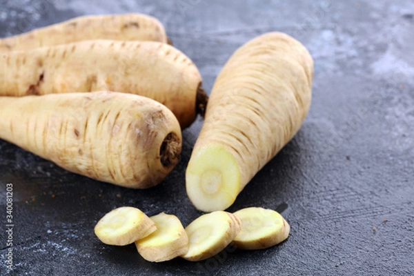 Obraz Parsnip root and slices on rustic background. Fresh raw organic parsnip