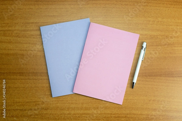 Fototapeta Stationery set with two colored empty notebooks and a white empty pen for mockup purposes