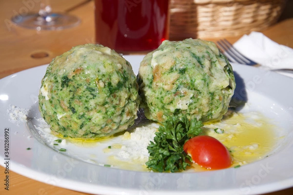 Fototapeta two fresh delicious green spinach dumplings on a plate with tomato and parsley herbs and butter sauce in alto adige alpin restaurant authentic liveauthentic
