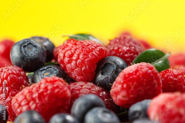 Fototapeta raspberry and blackberry on a yellow background.               