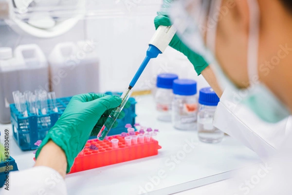 Fototapeta Close up scientist using pipette transfer sample to Micro Centrifuge Tube for PCR test in Biosafety cabinet.
