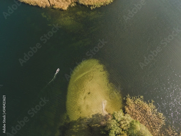 Obraz Aerial drone photo of small yacht sailing on lake Ukiel in Olsztyn, Masurian Lake District. Vertical drone view.