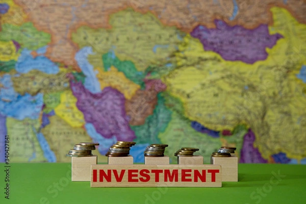 Fototapeta Metal coins against the background of a geographical map