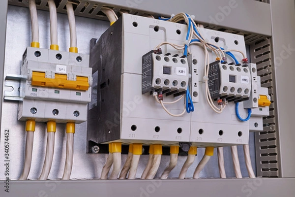 Obraz Two powerful power contactors with front additional contacts and two circuit breakers in the electrical Cabinet. Electrical wires are connected to electrical equipment. Maintenance and service.