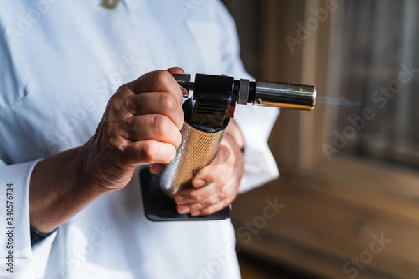 Fototapeta Cook using a kitchen torch with the flame coming out