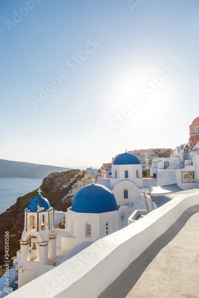 Obraz Famous blue dome churches in Oia, (Santorini, Greece) in the morning. White architecture of Oia village on Santorini island, Greece. Traditional tourism in mediterranean white architecture view
