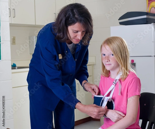 Obraz School nurse checking sling for broken arm