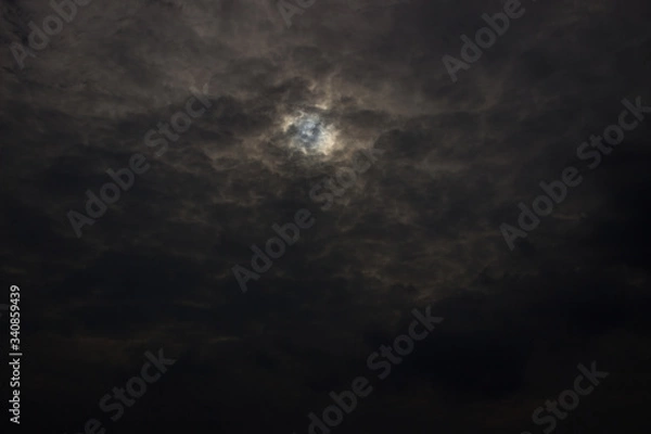 Fototapeta A shot of dark evening cloudscape with sun hiding behind
