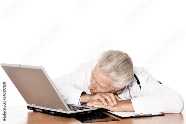 Obraz Elderly tired doctor with a laptop on white background