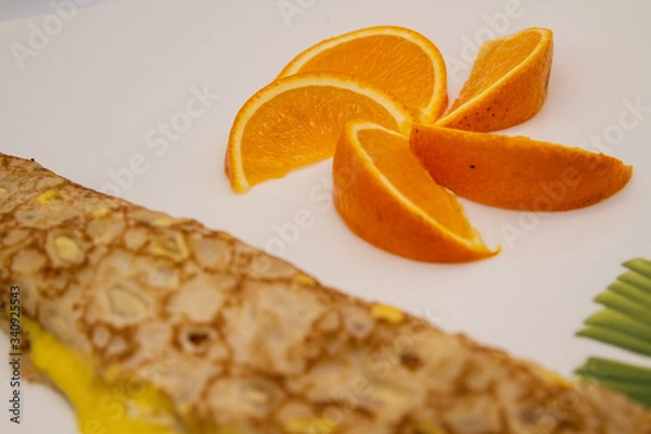 Obraz Crepe or french pancake with yellow mango cream and decoration of orange slices (close-up)