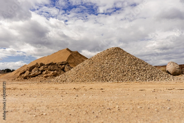 Fototapeta Open pit gravel mining. Large piles of construction sand and gravel used for asphalt production and building. Limestone quarry, mining rocks and stones. Sunny day