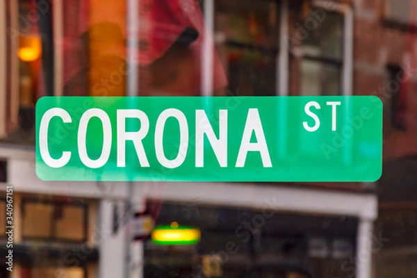Fototapeta Green street sign on a window with the text corona street with reflections in the back