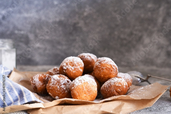 Fototapeta Fried donuts with icing sugar on the kitchen table.